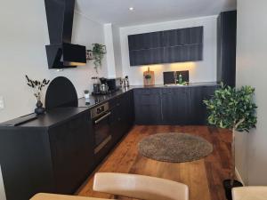a kitchen with black cabinets and a wooden floor at Romslig leilighet midt i Lofoten in Leknes