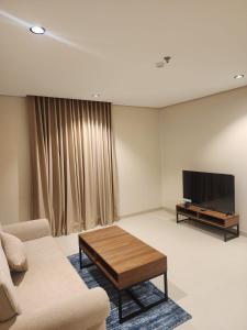 a living room with a couch and a flat screen tv at المهيدب للشقق الفندقية in Rabigh