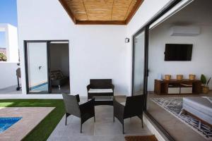 a living room with chairs and a couch and a television at Exclusive pool house in Bahía Kino