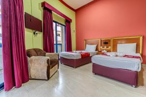 a hotel room with two beds and a chair at City Relax Hotel in Dubai