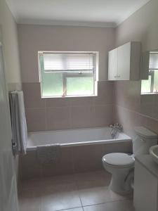 a bathroom with a tub and a toilet and a window at Sea Cottage in Noordhoek +27 photos