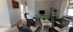 a living room with chairs and a table and a tv at Sea Cottage in Noordhoek