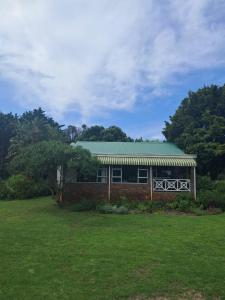 a brick building with a green roof on a field at Sea Cottage in Noordhoek