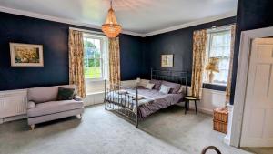 a bedroom with a bed and a couch and windows at Charming 1700s Country Cottage on a Private Estate in Stirling