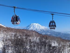 a ski lift with a snow covered mountain in the background at TR Niseko House Room New York in Niseko