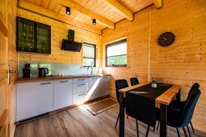 a kitchen and dining room with a table in a cabin at Przystanek Kistówko komfortowe domki z jacuzzi, staw wędkarski, kominek, las, przestrzeń in Kistowko