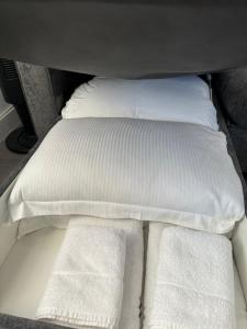 a bed with white sheets and pillows in a car at Spacious modern 1-bed apartment near Victoria Park & London Stadium in London
