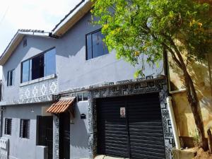 a white house with a black garage at Hospedaria Oliveira - São Thomé das Letras in São Thomé das Letras