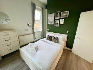 a bedroom with a white bed with a green wall at Spacious modern 1-bed apartment near Victoria Park & London Stadium in London