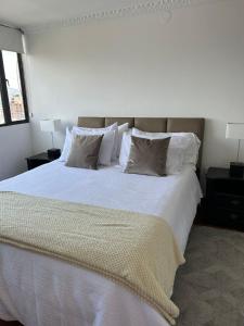 um quarto com uma cama grande com lençóis e travesseiros brancos em Suite amoblada con aparcamiento privado excelente vista y ubicación! Sector La Carolina em Quito