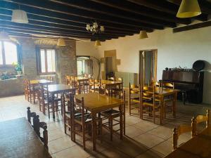 a restaurant with wooden tables and chairs and a piano at Angrill in Lladurs