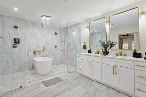 a bathroom with two sinks and a tub and a mirror at 3-BD Backyard Oasis w Pool Patio Firepit in Irving