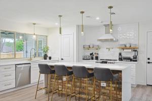 a white kitchen with a large island with bar stools at 3-BD Backyard Oasis w Pool Patio Firepit in Irving