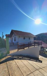 a white building with a bench on the side of it at Chalés Leopoldo em Monte Verde in Monte Verde