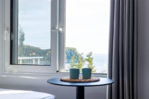 a table with two cups on it in front of a window at Hi'Mare TOP Sea View 1 - Parking and Kitchen in Himare