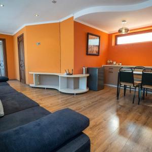 a living room with orange walls and a table and chairs at Vardisubani Villa in Kazbegi