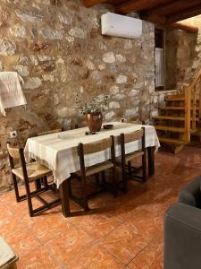 a dining room with a table and chairs and a stone wall at Pedra in Gerolimenas