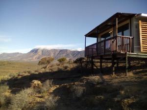 a cabin in the desert with mountains in the background at Romantic Cottage in Barrydale