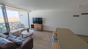 a living room with a couch and a flat screen tv at Departamento Nuevo Cerca de la Playa in Bahia Inglesa