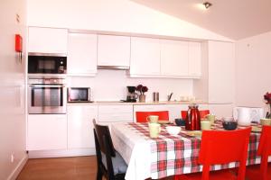 una cucina con mobili bianchi e un tavolo con sedie rosse di Casa da Cerca a Óbidos