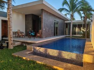 a villa with a swimming pool in front of a house at Desarrollo Ohana I Playa Blanca in Zihuatanejo
