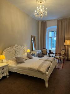 a bedroom with a large white bed and a chandelier at Csaky palace 2 Bratislava in Bratislava