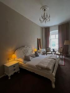 a bedroom with a large white bed and a chandelier at Csaky palace 2 Bratislava in Bratislava
