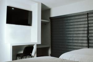 a bedroom with two beds and a chair and a tv at LONGVIEW HOME-STUDIOS in Tepic