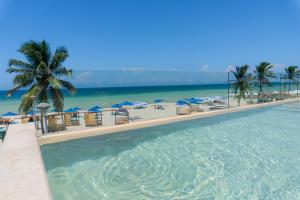 a large swimming pool next to the beach with umbrellas at Hotel Scappata in Progreso