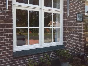 ein weißes Fenster auf einem Backsteingebäude mit in der Unterkunft B&B In De Backerije 2 in Zuidwolde