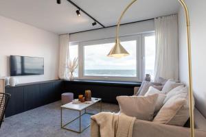 a living room with a white couch and a large window at Wonderful architect designed flat with sea view in Ostend