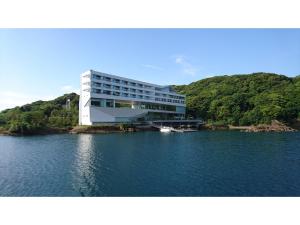 a building on a lake with a boat in the water at Olive Bay Hotel - Vacation STAY 91402v in Saikai