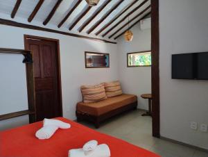 a room with a bed and a couch and a television at Casa Paiol loft no centro do Arraial in Arraial d'Ajuda