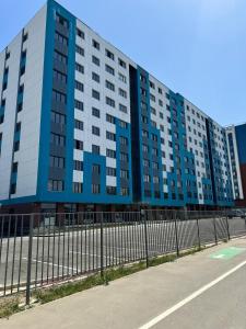 a large blue and white building with a fence at Студия красивая in Almaty