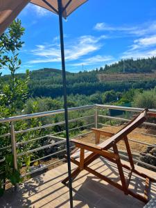 Un banco de madera sentado en una terraza con una sombrilla. en Casa do Beco, en Moninho