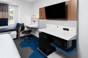 an office with a desk and a tv on a wall at Microtel Inn by Wyndham Janesville in Janesville