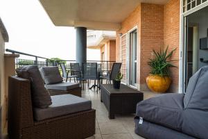 Un patio con sillas y un sofá en un balcón. en Residenza dell Agrifoglio, en Mostacciano