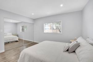 a white bedroom with a bed and a mirror at Valley Ranch With Pool in Los Angeles +12 photos
