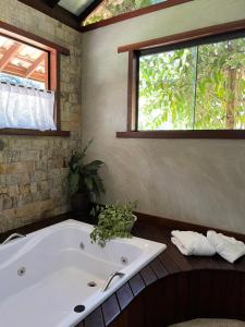a bath tub in a bathroom with a window at Matha Pousada e Bistrô in Lumiar