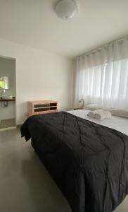 - une chambre avec un grand lit et une couverture noire dans l'établissement Espaço Villa Pella - Chalé Peônia, à Brumadinho