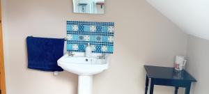 une salle de bain avec un lavabo et un mur en carrelage bleu dans l'établissement Lakeview, à Castlefore 3 autres photos