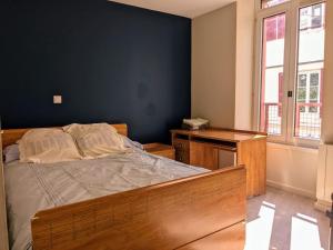 a bedroom with a bed and a desk and window at Bel appartement en rue piétonne in Roanne