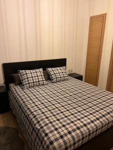 a bed with a checkered blanket and two pillows at 2 bedroom apartment with sea view and private pool in Sidi Bouqnadel +17 photos
