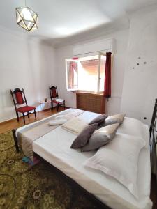 Una cama blanca grande en una habitación con ventana. en 雅典市电影舒适酒店公寓, en Atenas