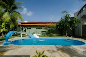 a pool with a slide in front of a house at LC Casas de Praia - Chalé 3 centrinho de Porto in Porto De Galinhas