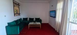 a living room with a green couch and a table at Jolie Villa vue montagne et piscine privée in Tangier