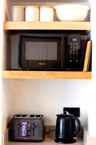 a black microwave oven sitting on a shelf with a toaster at Wellington House Boutique Holiday Let in Falmouth