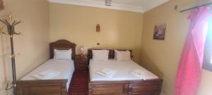 une chambre avec deux lits avec des draps blancs dans l'établissement Maison d'Hôtes Ghalil, à Ouarzazate