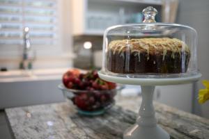 a cake in a glass dish on a counter with a bowl of fruit at Ms. Bunny's Bungalow in Fredericksburg