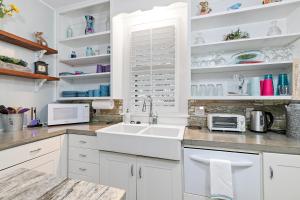 a kitchen with white cabinets and a sink at Ms. Bunny's Bungalow in Fredericksburg +41 photos